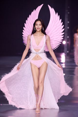 Liu Wen walks down the Victoria's Secret Fashion Show runway wearing pink wings and a pink bralette