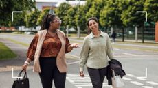 Two women walking together, laughing and smiling, to get 10,000 steps a day