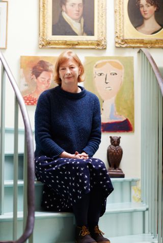 Vanessa Arbuthnott sitting on painted stairs in her converted cow barn home