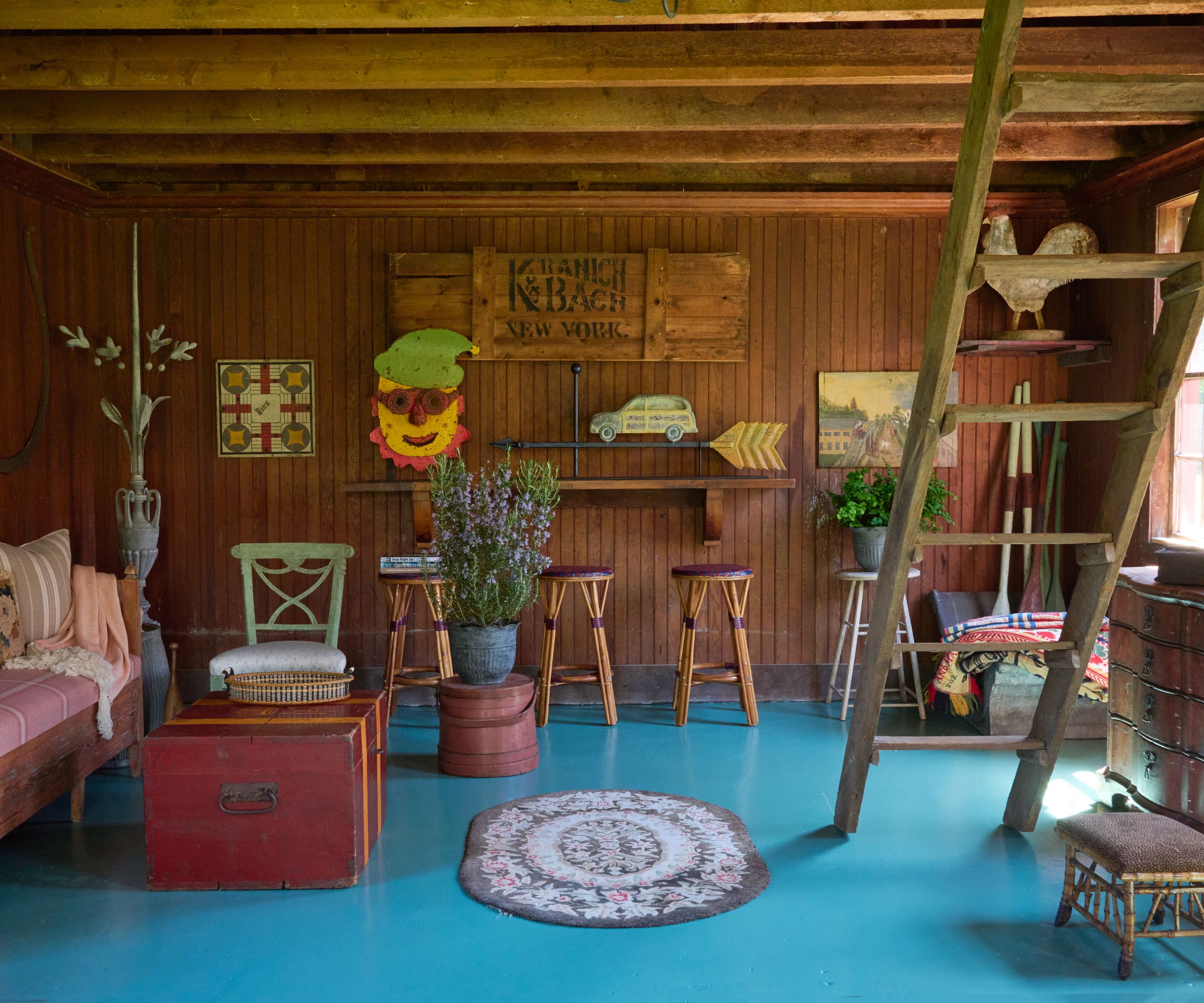 Wood panelled barn with painted blue flooring filled with antiques