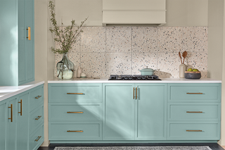 A kitchen with light blue cabinetry and terrazzo tile backsplash
