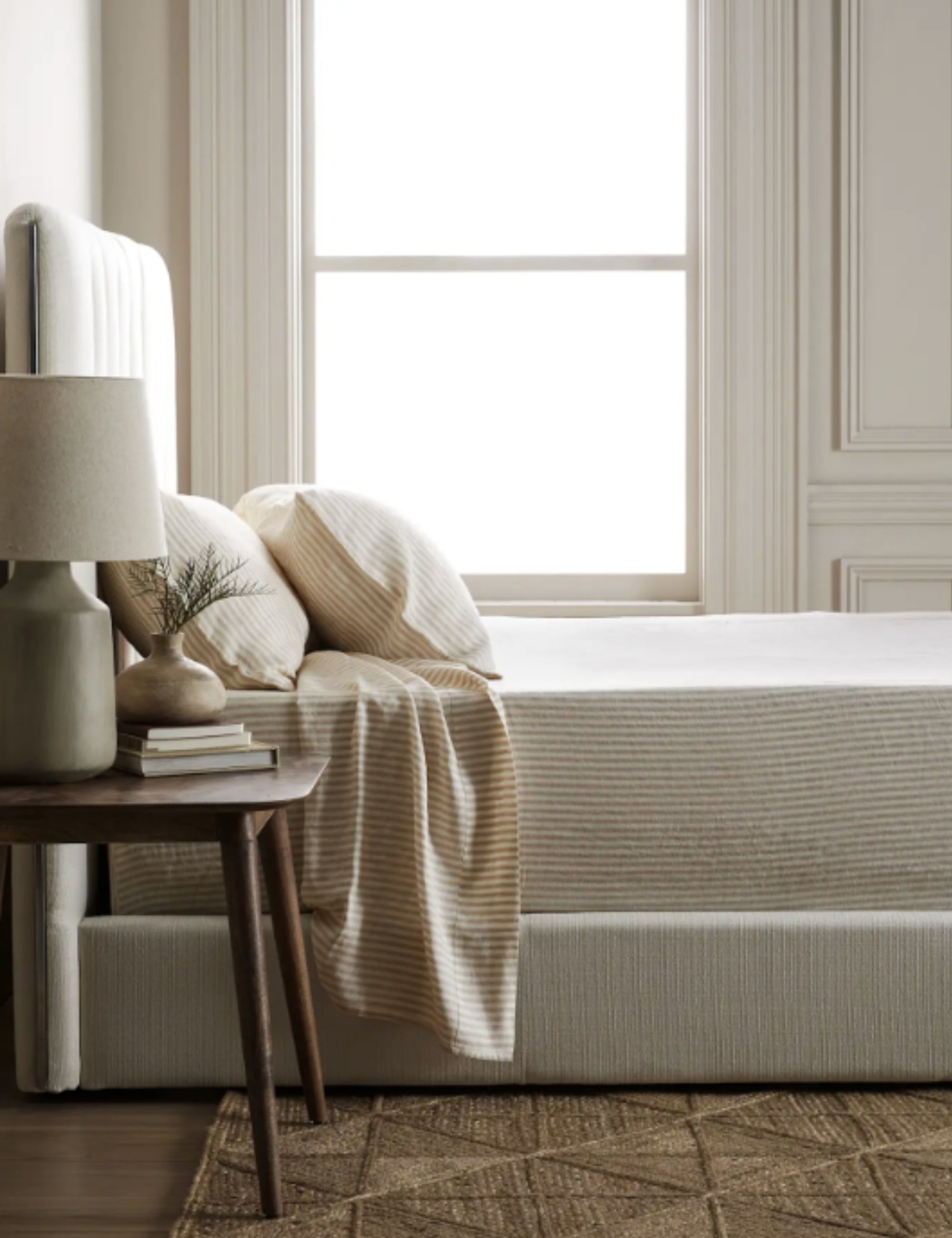 Quince latte striped bed sheets styled inside a bright white bedroom with decorative molding