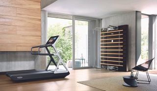 An exercise area with a treadmill, exercise equipment on the wall, a chair and sliding doors.
