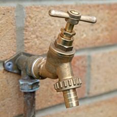 Gold outdoor tap on a bright wall 