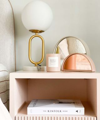 pink bedside table with lamp, mirror and candle