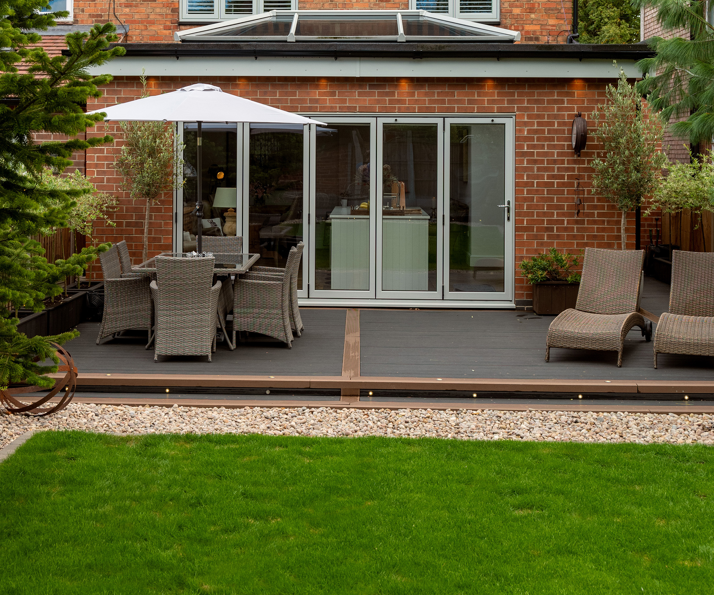 Lawn edged with about a foots width of gravel, separating lawn from a deck