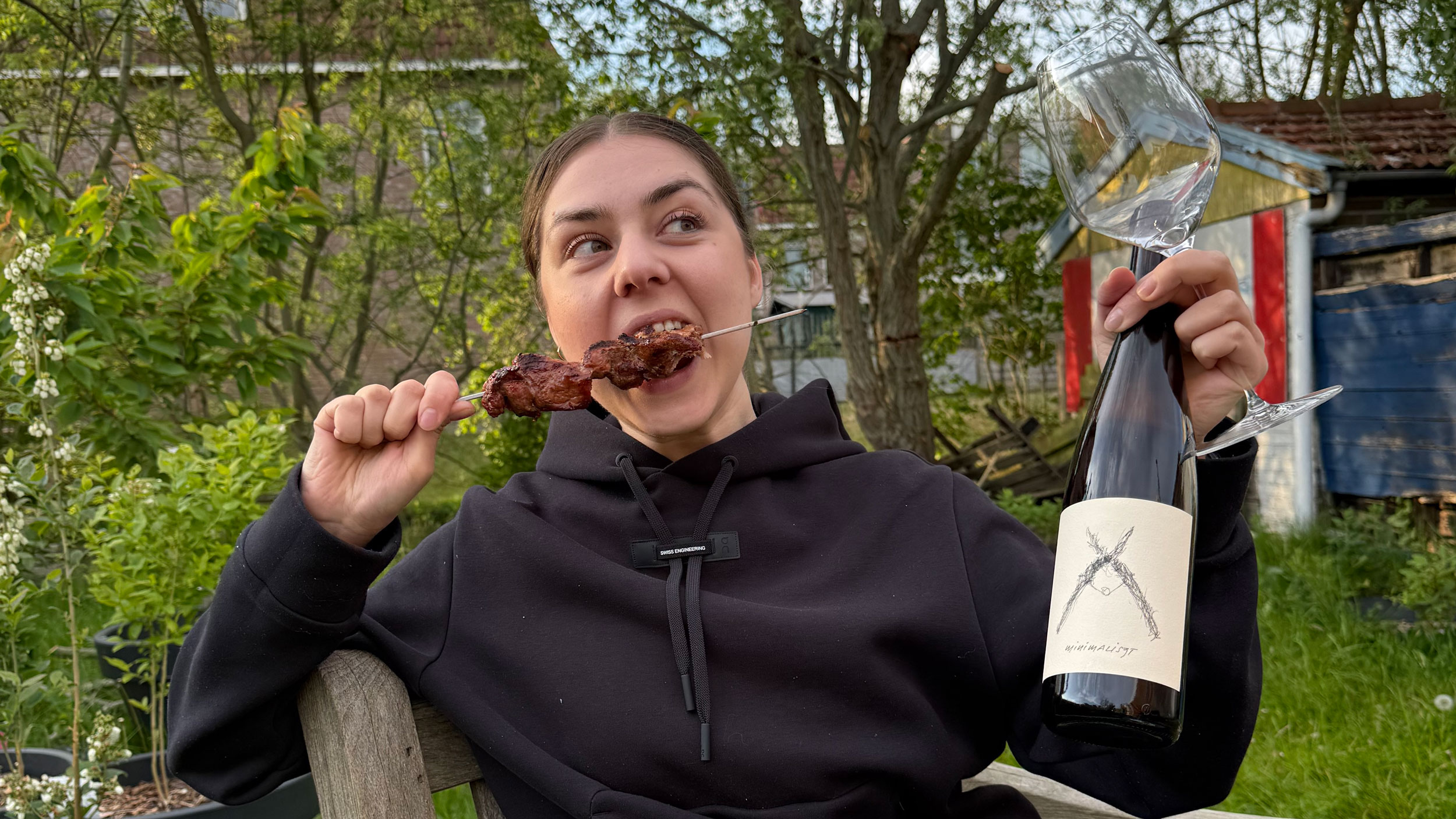 Daria Volokitina eating a kebab and holding a glass and bottle of Austrian Furmint