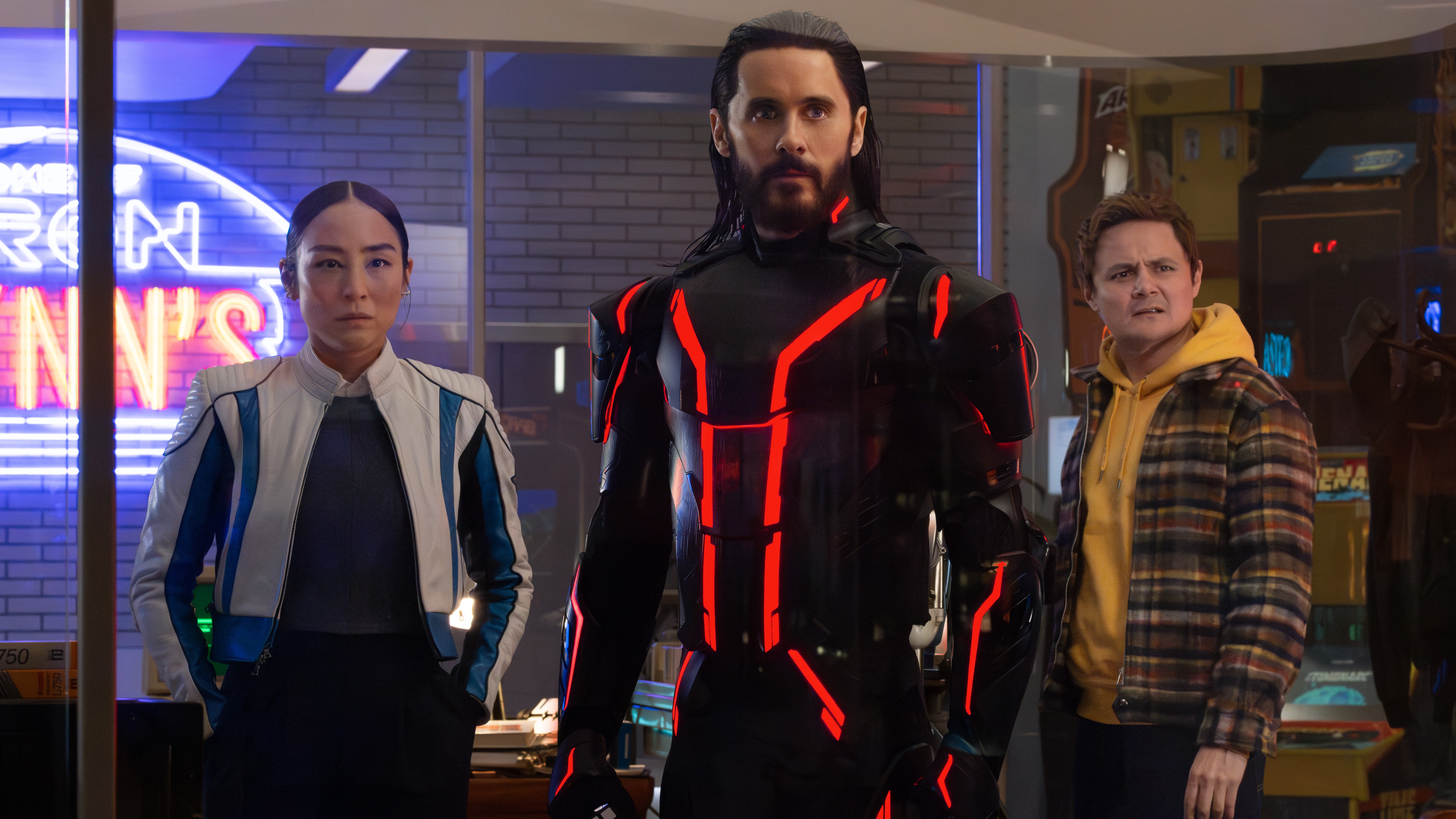L-R: Eve Kim (Greta Lee), Ares (Jared Leto) and Seth (Arturo Castro) in a scene from Disney's "TRON: Ares"