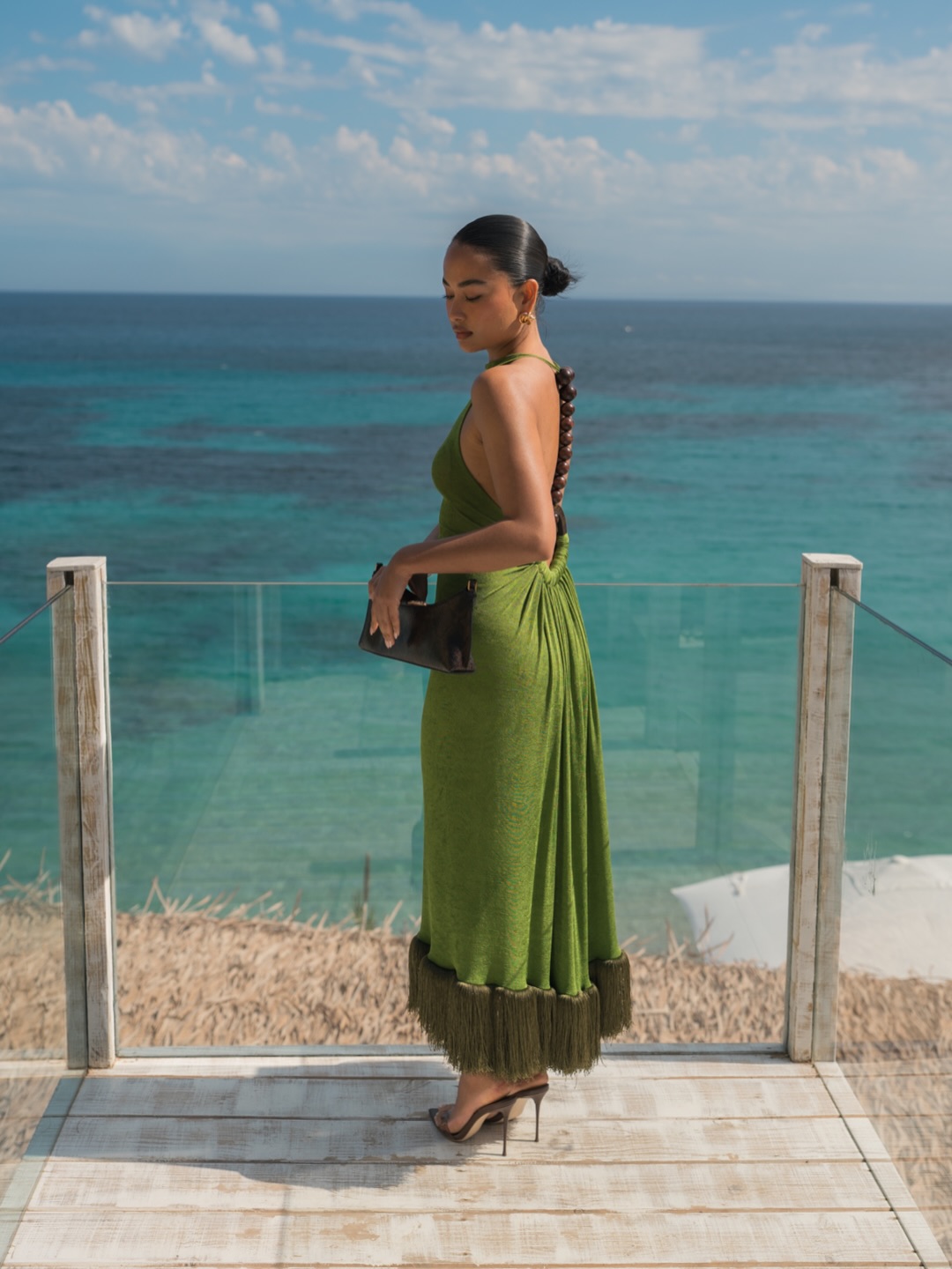 Influencer Aanisha Gurung wearing a green fringed dress, stilettos and a clutch bag.