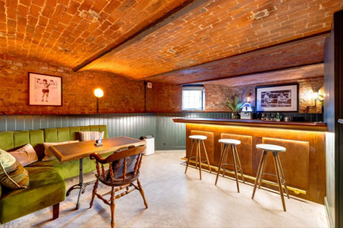 A brick cellar with a bar and a green sofa