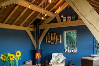 oak framed garden room with dark blue walls and exposed bulb lighting