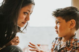 A woman making eye contact with a young boy while he is talking to her