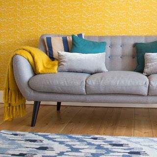 living room with bright yellow wallpaper and grey sofa