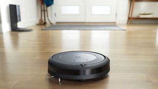 The iRobot Roomba i3 cleaning a hard wood floor in a hallway