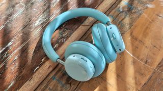 CMF Headphone Pro; a pair of light green headphones on a wooden table