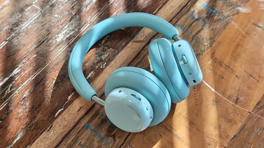 CMF Headphone Pro; a pair of light green headphones on a wooden table