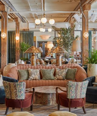 Coral colored sofa with pillows with lower coffee table and two armchairs facing