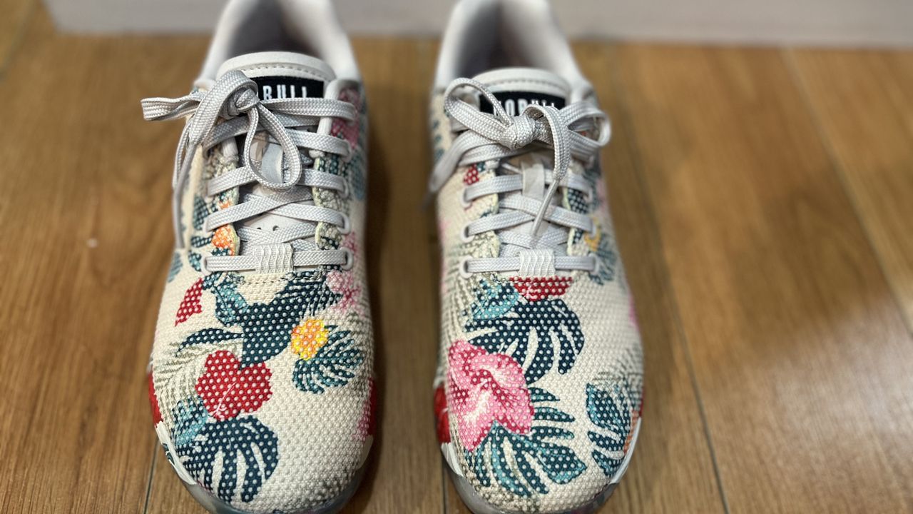 NoBull Outwork training shoes with tropical print resting on a wooden floor.
