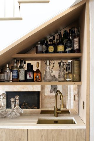 small home bar under stairs with shelving, mirror and sink