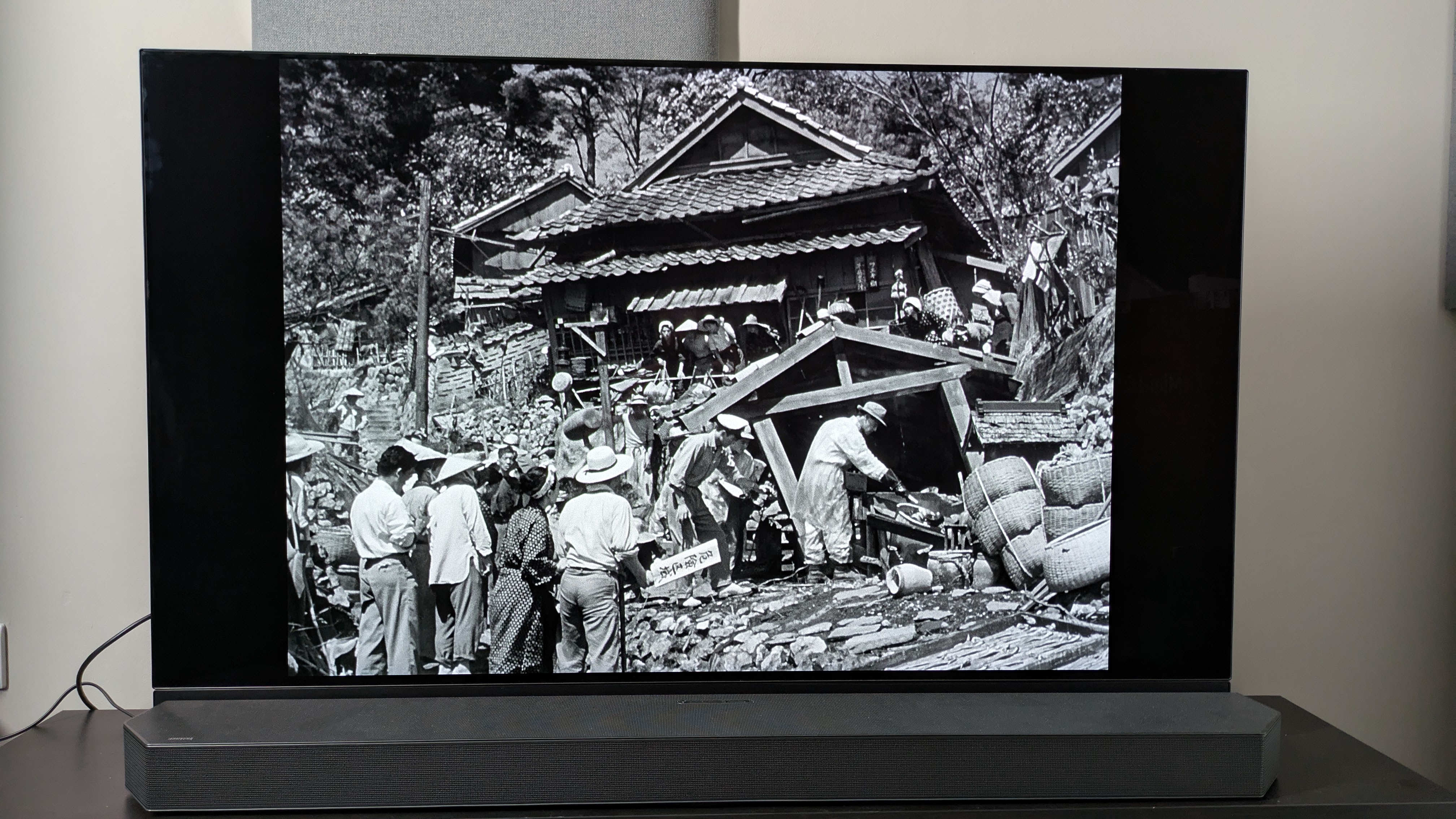 Godzilla (1954) image of villagers on Panasonic MZ1500 OLED with HW-Q990C soundbar in front of TV