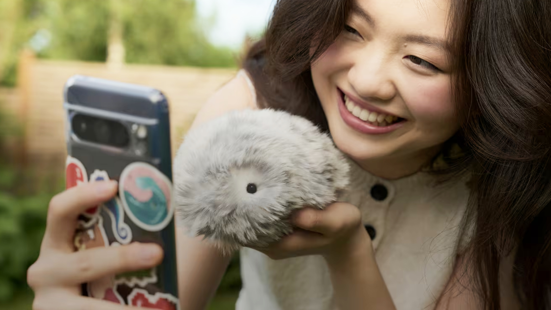 A Casio Moflin, being held up in front of a camera by a beaming model