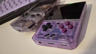 Photo taken by writer Rosalie Newcombe of the Miyoo Mini Plus sitting on a white desk with a Game Boy Color sitting to the left of it.