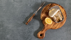 Tinned sardines on wooden board with a slice of lemon