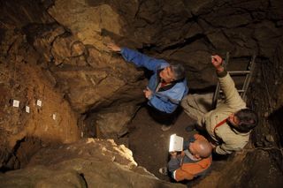Researchers Maxim Kozlikin, Vladimir Uliyanov and Richard 'Bert' Roberts stand in the east chamber of Denisova Cave.