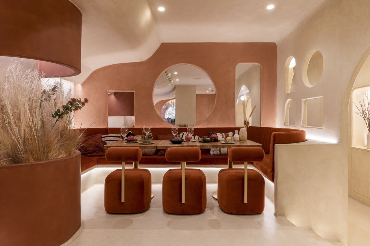 An underground restaurant wrapped in a palette of ivory, dusty rose and deep rust red, with geometric cut outs in the walls.