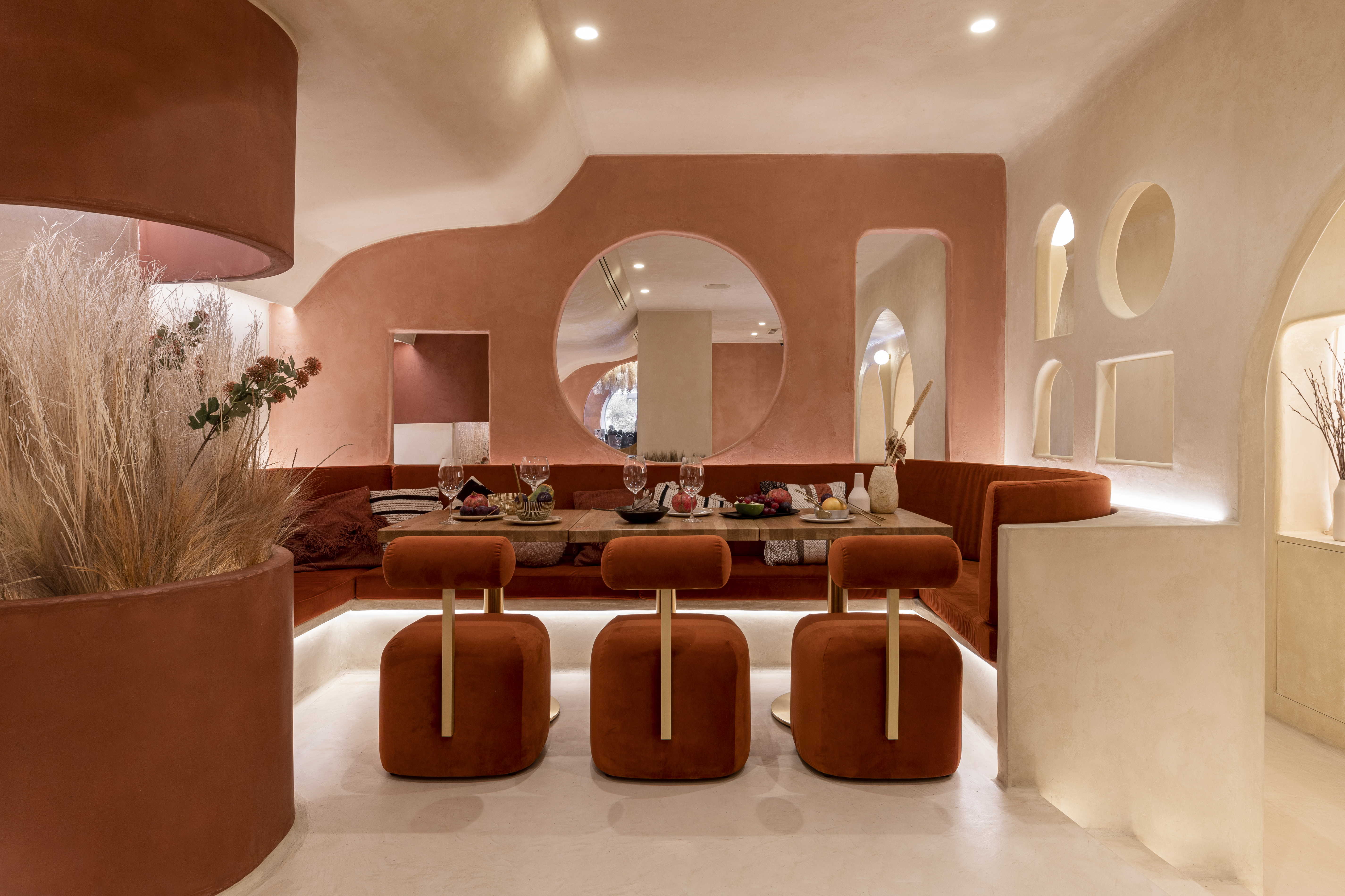 An underground restaurant wrapped in a palette of ivory, dusty rose and deep rust red, with geometric cut outs in the walls.
