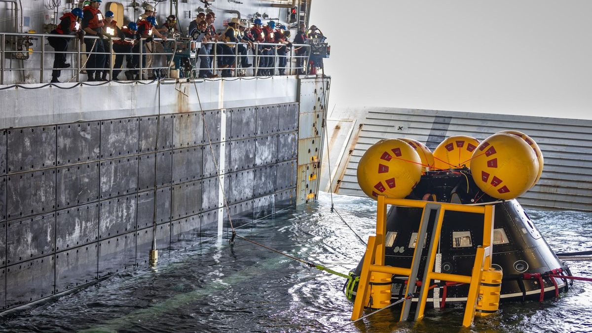 During an Artemis 2 splashdown exercise on July 26, a simulated spacecraft known as the Crew Module Test Article is visible at the U.S.S. John P. Murtha warship in the Pacific Ocean. NASA and the U.S. Navy worked together to practice recovery operations for the moon mission scheduled for late 2024.