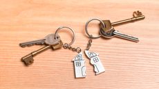 Two sets of keys sharing one key chain shaped like a house that's split in half. 