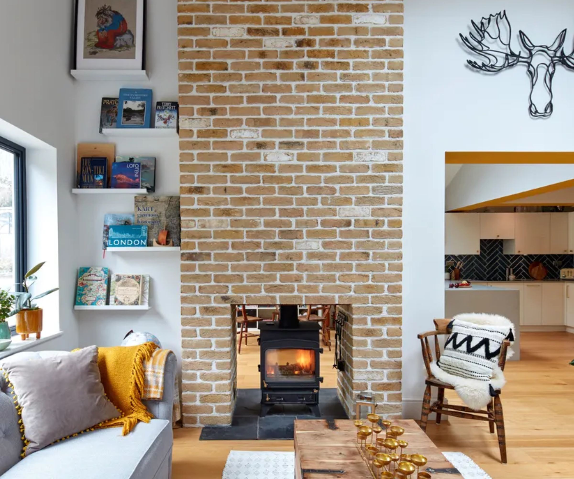 A double sided log burner positioned within a large exposed brick chimney breast