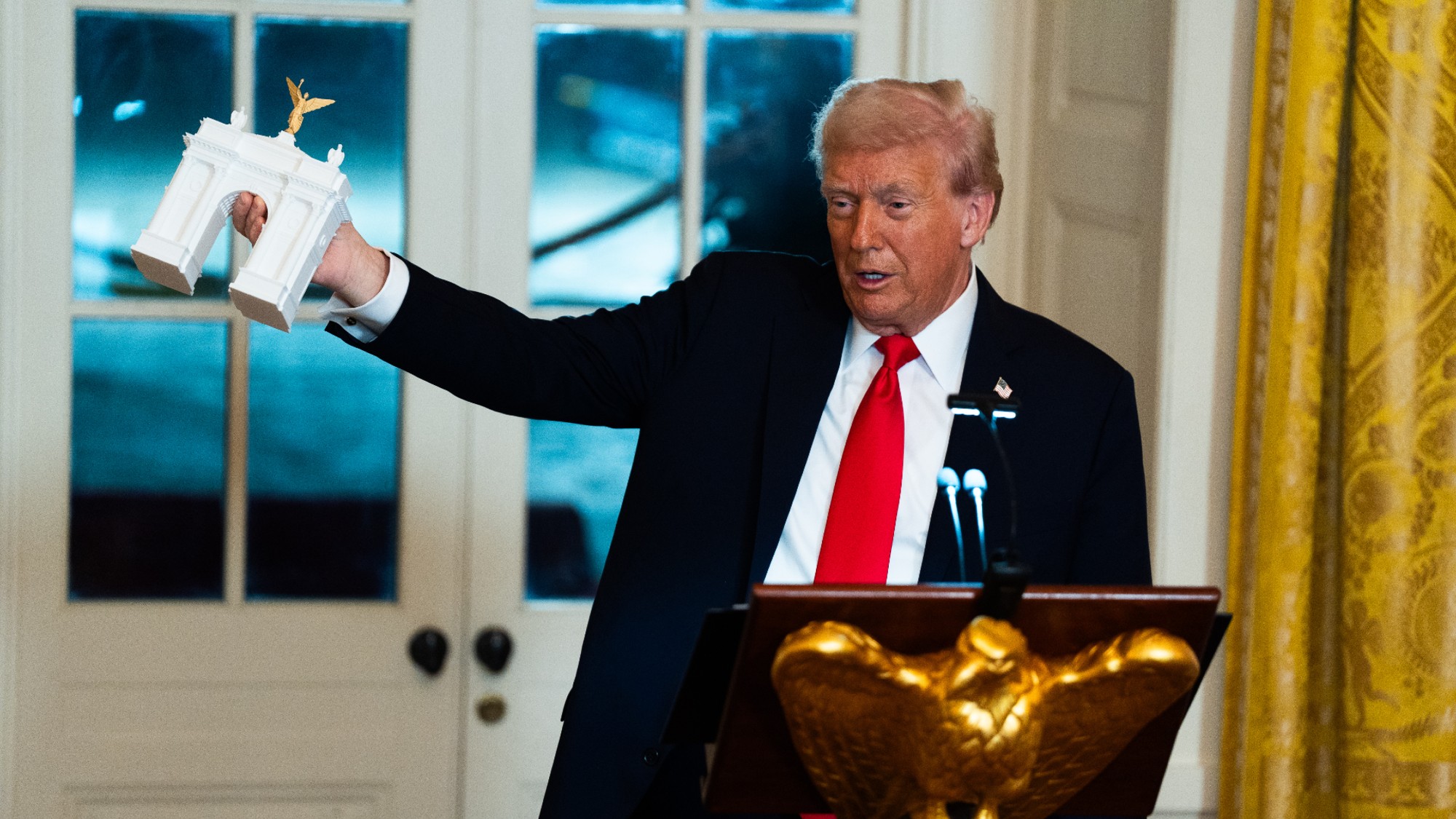President Donald Trump holds up a model of his planned arch in Washington, D.C. 