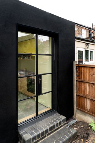 extension cladding witha pair of doors leading onto the inside kitchen, and with brick steps down into the garden