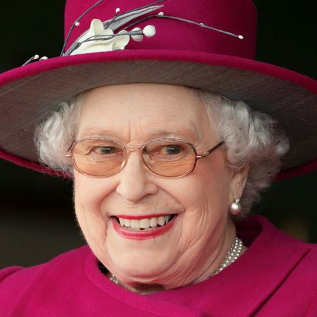 Queen Elizabeth wearing a magenta hat and coat looking excited