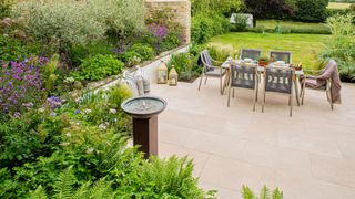 large patio surrounded by planting with an outdoor dining area and water feature