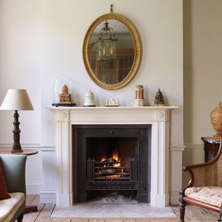 Regency fireplace with stone surround in minimalist living room with white walls and gold framed mirror jamb
