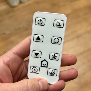 A white remote control being held in a woman's hand