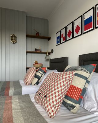 twin boys' bedroom with nautical theme, painted shiplap, open shelving, nautical style lights, gray, red and blue bed pillows and blankets, artwork