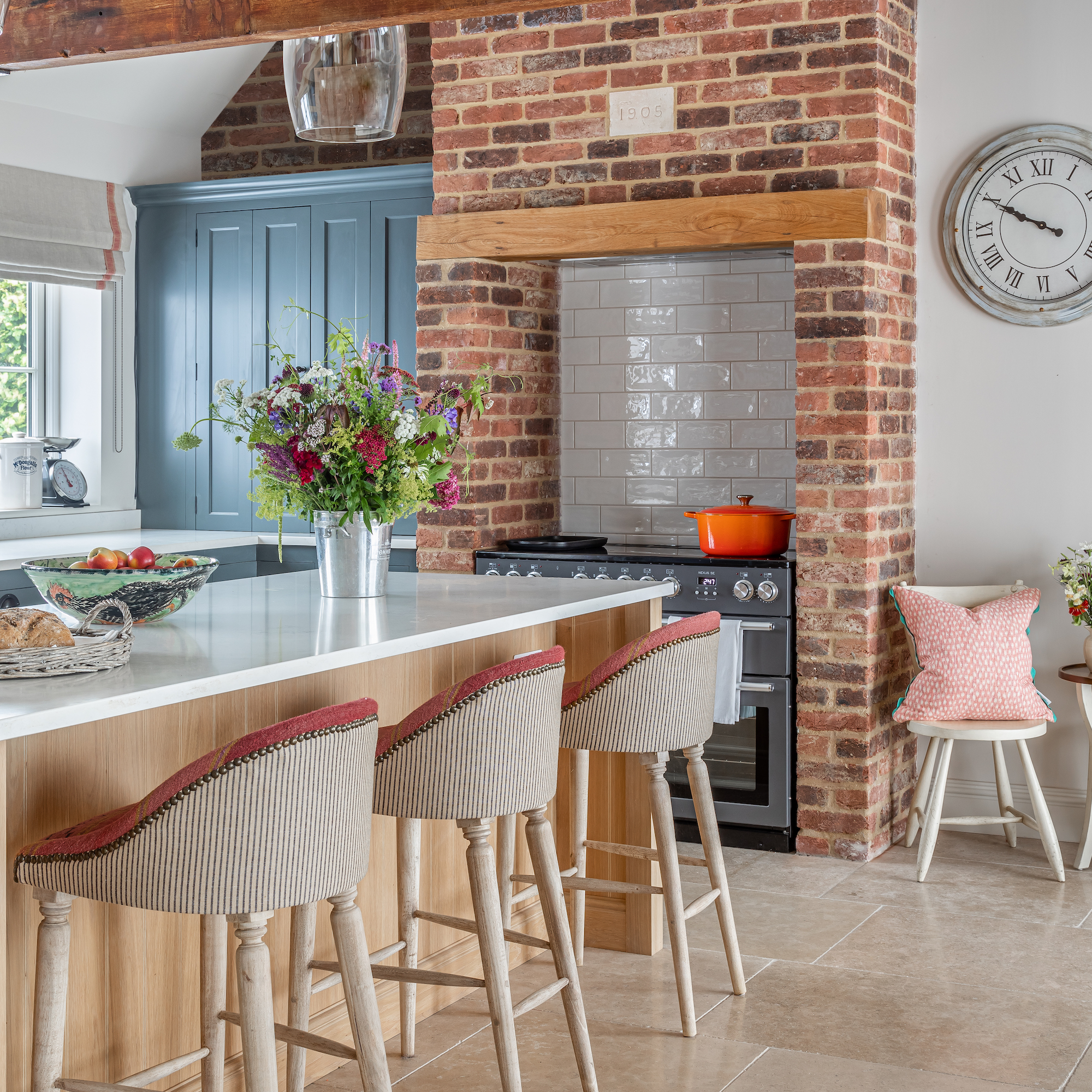 kitchen with brick chimney around range cooker and wooden island unit with bar stools