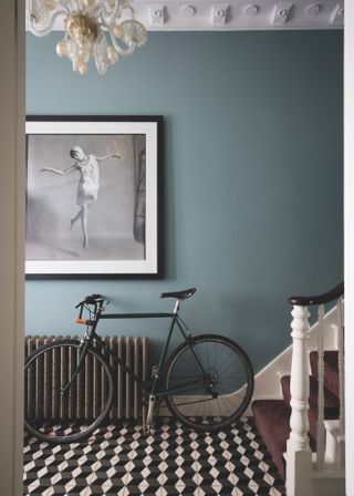 Small blue entryway with tiled floor and accessorized with a push bike and artwork.