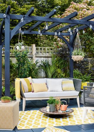 Hanging baskets on modern pergola with outdoor sofa