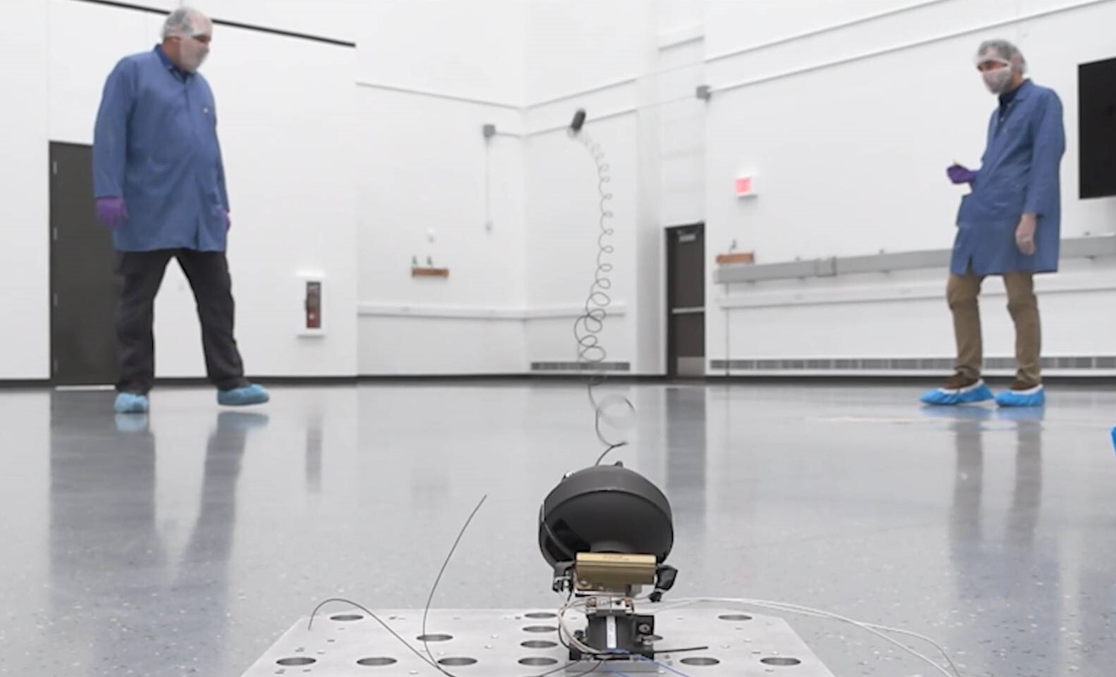 Two men test a piece of equipment in an empty room.
