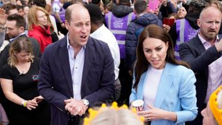 Prince William, Prince of Wales stands next to Catherine, Princess of Wales as they speak to people during a walkabout
