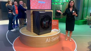 Grundig's AI-sense washing machine on the company's stand at IFA 2023, with a woman presenting next to it