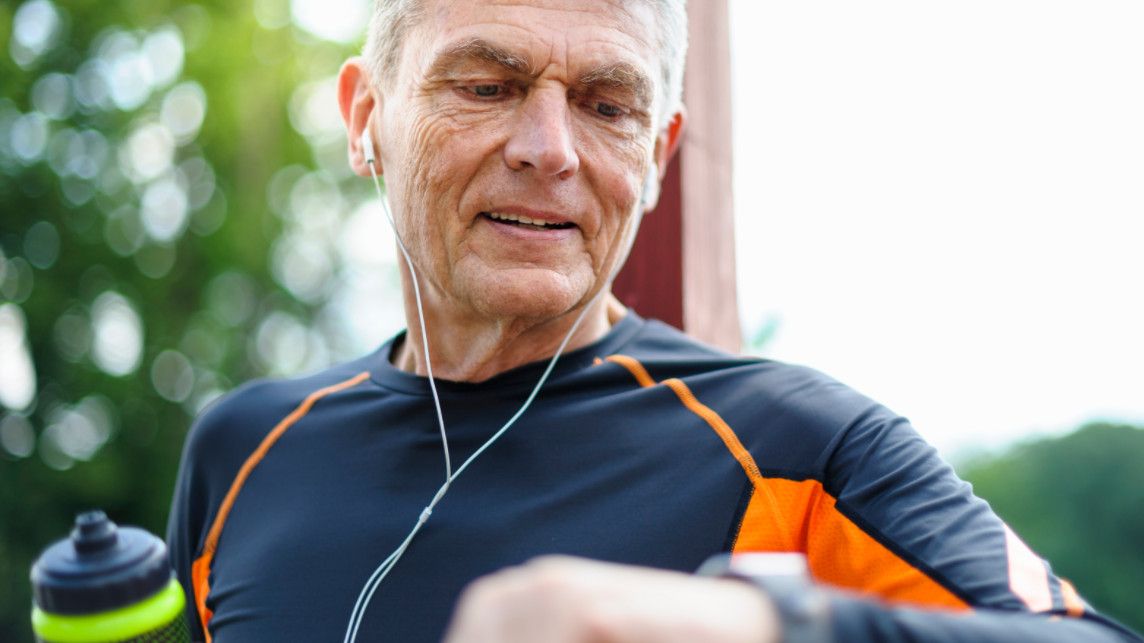 Man running outdoors using fitness tracker