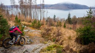 mountain biker riding down rocks by Scottish loch