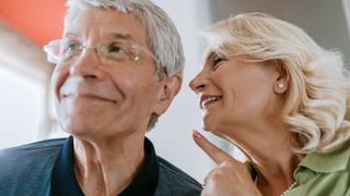 Woman talking into her husband's ear to help clear communication despite hearing loss