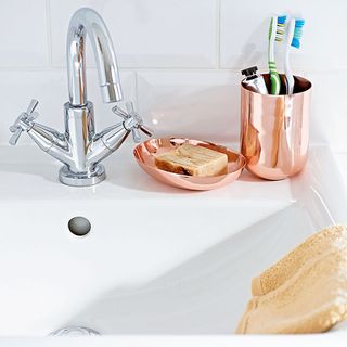 wash basin silver tap and toothbrush and sope holder and yellow towel